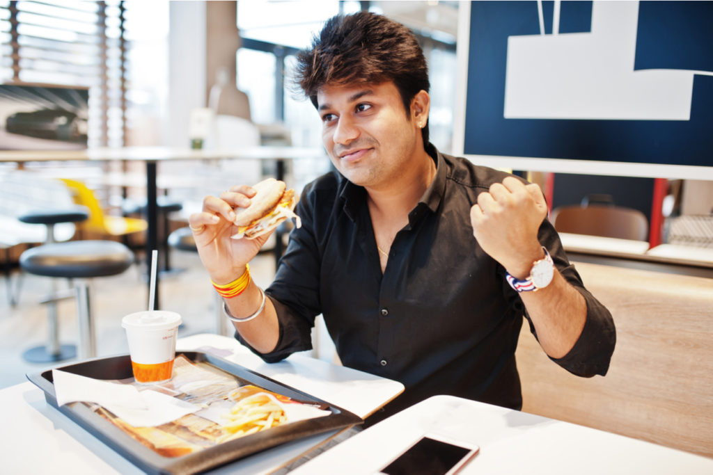young business man eating a burger and fries