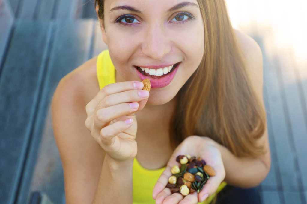 young woman eating trail mix outside